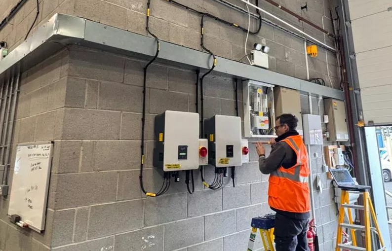 Man installing two battery storage units on wall.